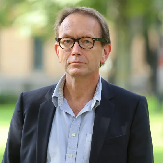 Man med ljus skjorta och mörk kavaj med glasögon