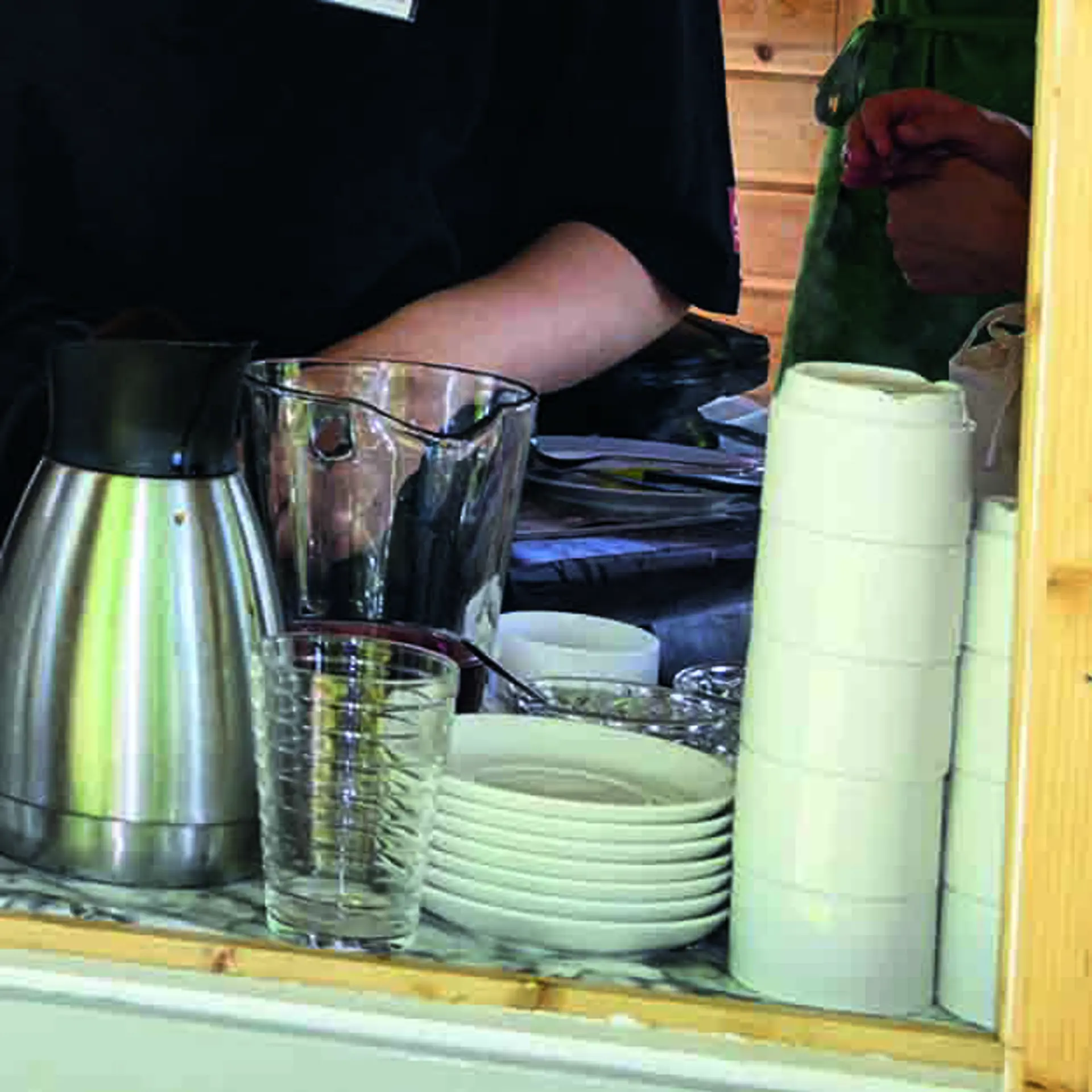 Glas, koppar och fat staplade i ett öppet fönster till ett café.