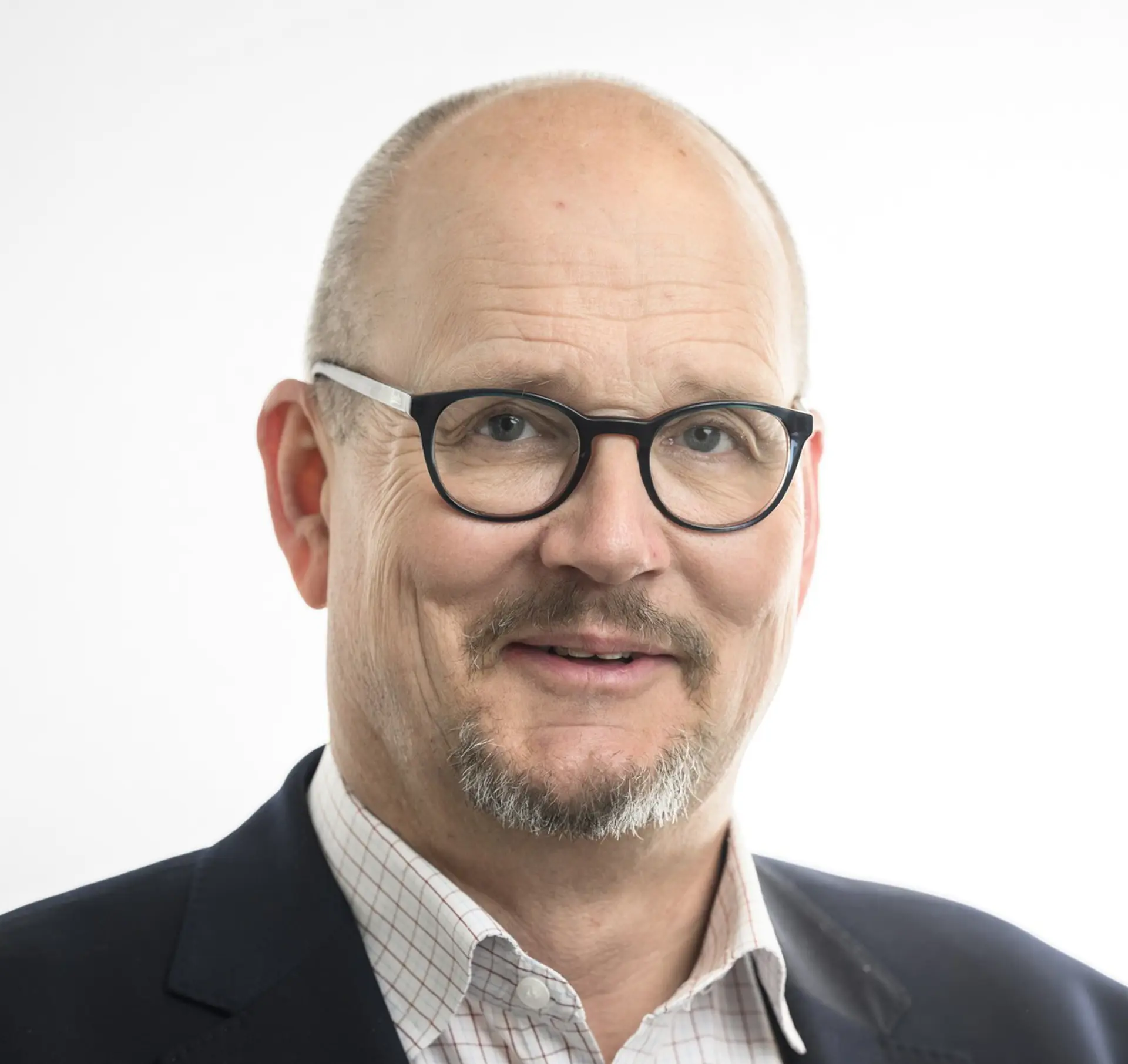 Man med kal hjässa, mörka glasögon, skjorta och kaval.